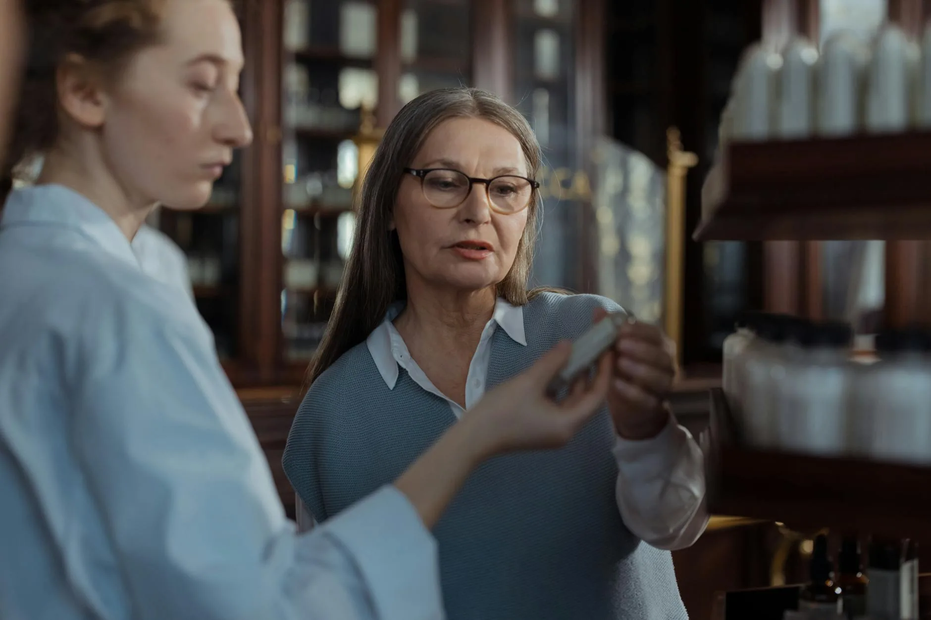 Senior pharmacy customer reviewing prescription with a pharmacist