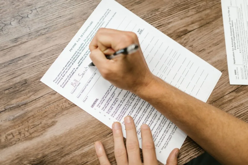 A person filling out a tax form at a desk with a calculator and documents